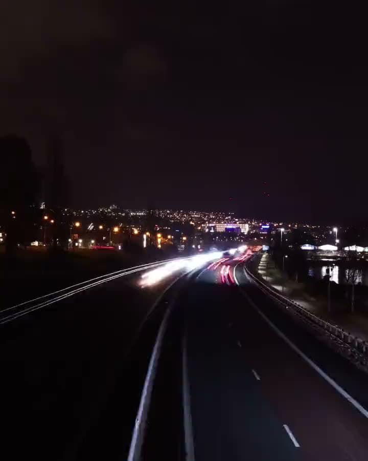 Red and white light trails streaming down a night highway.